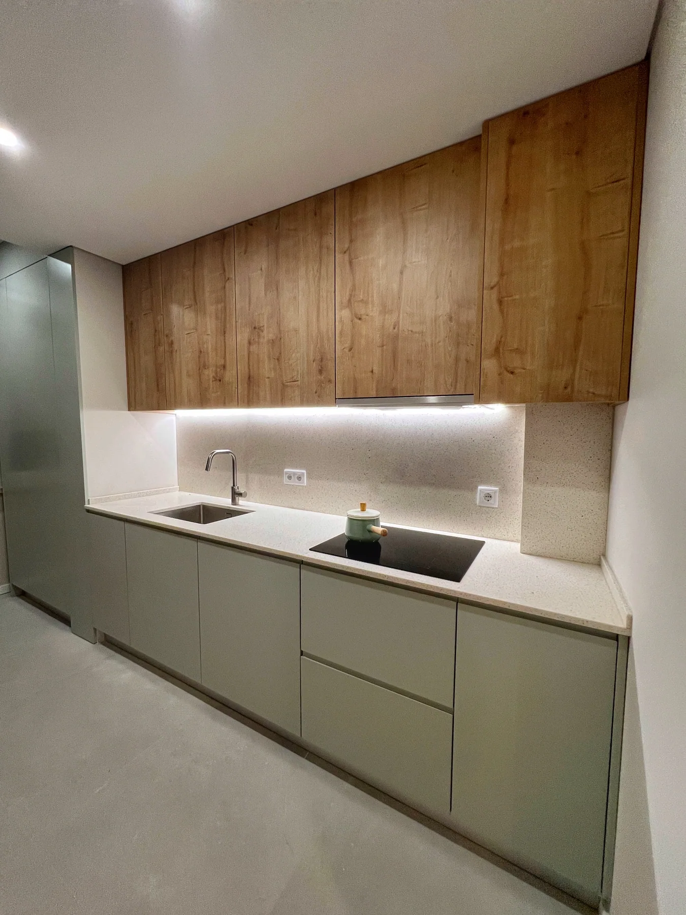 Cozinha concluída da Casa Âmbar, com armários em madeira e verde-sálvia