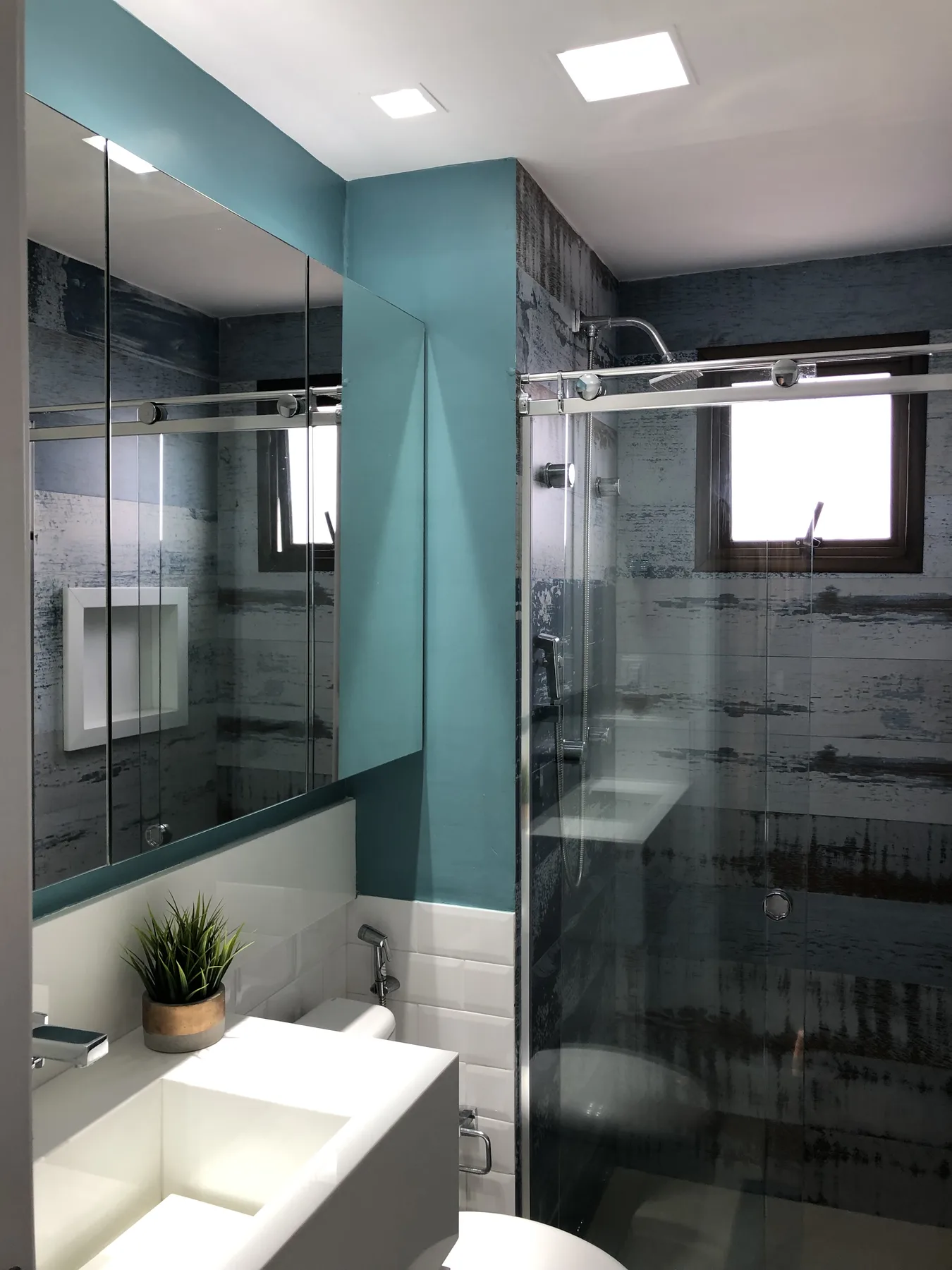 Casa de banho com parede verde azulada e duche envidraçado