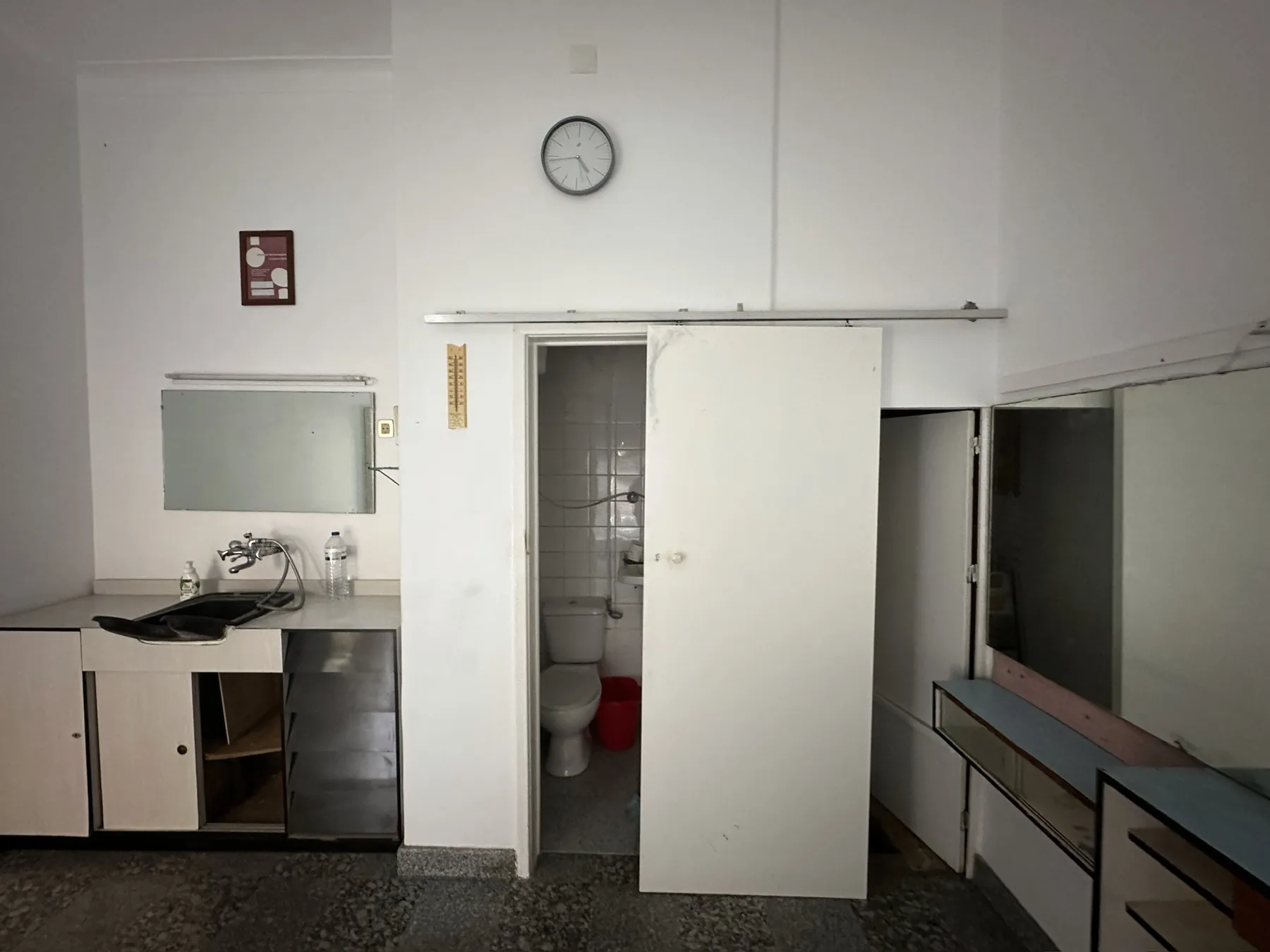 A parede do lavabo antes da obra, com porta de correr antiga e bancada de cabeleireiro