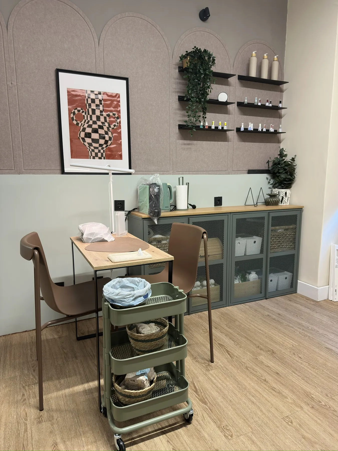 Mesa de manicure, prateleiras e armários verdes junto à parede com arcos